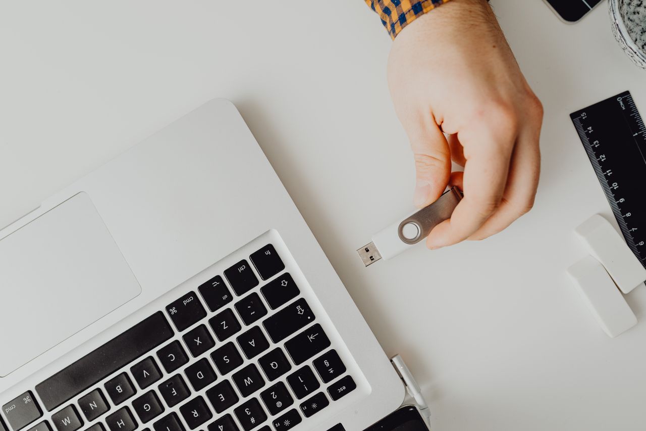 Hand inserting USB drive into laptop. Modern tech connection concept.