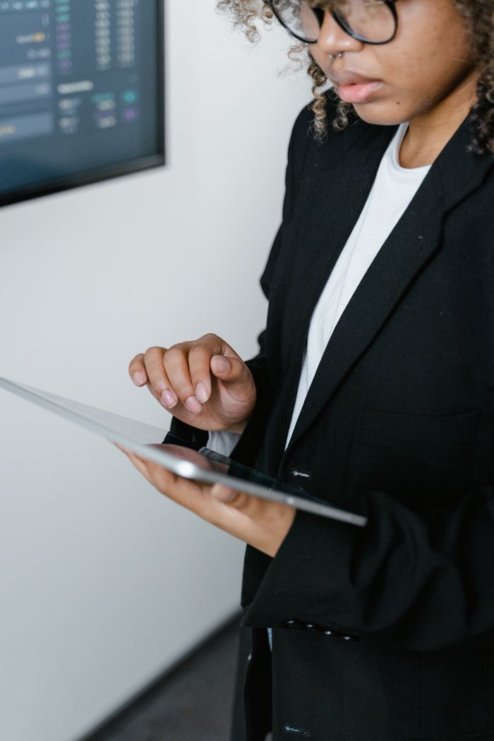 Professional woman interacts with a digital tablet in an office environment, showcasing technological engagement.